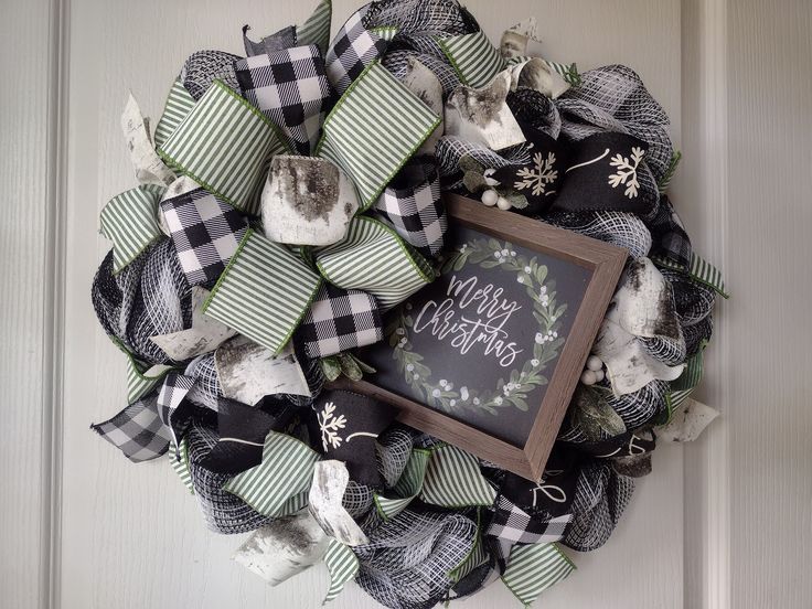 a wreath with a chalkboard on it and some bows hanging from the front door