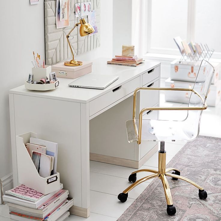 a white desk and chair in a room with pictures on the wall behind it, along with other office supplies