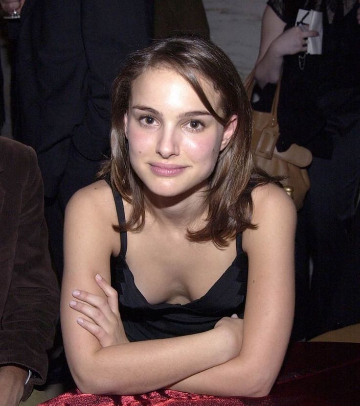 a young woman sitting at a table with her arms crossed and looking into the camera