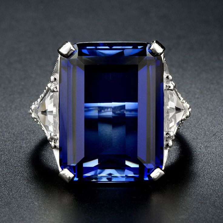 A stunning dress ring made in 9ct white gold and handset with a large 25-30 carat lab created Blue sapphire and complimented by trillion cut 5-8mm Lab created White Sapphire on each side and accent high quality CZ stones We can make this design with your choice of gemstones and offer Platinum, Palladium, 9K, 10K, 14K or 18K Yellow, Rose or White Gold. Please convo us with your desired metal and gemstones and finger size and we will happily quote you a price. Please do note that as this design is Formal Sapphire Ring With Radiant Cut, Elegant Blue Sapphire Ring With Radiant Cut, Formal Radiant Cut Sapphire Ring, Elegant Blue Radiant Cut Sapphire Ring, Elegant Sapphire Ring With Emerald Cut, Elegant Radiant Cut Sapphire Ring, Luxury Sapphire Birthstone Ring For Formal Occasions, Elegant Sapphire Ring As Gift, Luxury Lab-created Sapphire Ring With Diamond Cut