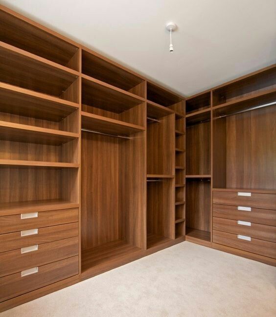 an empty walk in closet with wooden shelves and drawers