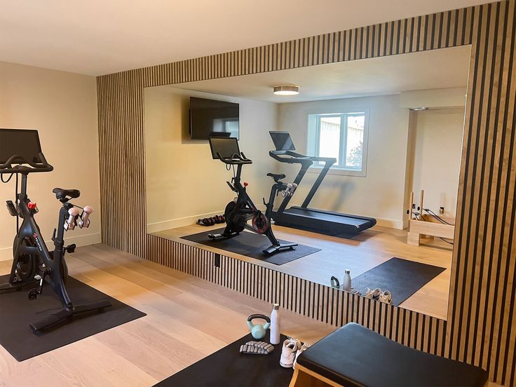 an exercise room with treadmills and other equipment on the floor in front of a large mirror