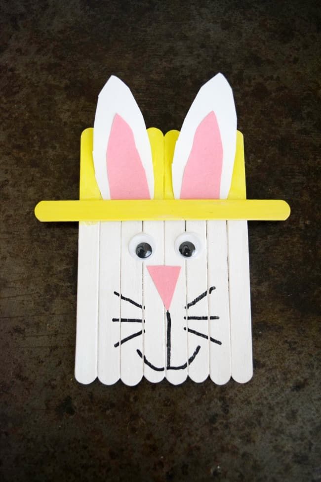 a paper bunny with a hat on it's head and ears made out of popsicle sticks