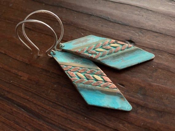 These earrings feature mixed metals of solid, gold brass & raw copper and are finished with a unique turquoise verdigris patina.  The patina has been sealed with a good coating of renaissance wax but should not be worn while showering or bathing to maintain patina.  The ear wires are forged by hand from 20g Sterling silver. These earrings have a celtic /  tribal feel.  They are versatile and suitable for just about any style, from modern to rustic. They're substantial but comfortable to wear Copper Dangle Earrings With Patina, Copper Dangle Jewelry With Patina, Soldered Turquoise Brass Earrings, Turquoise Soldered Brass Earrings, Artisan Turquoise Earrings In Copper, Artisan Turquoise Copper Earrings, Nickel-free Turquoise Copper Jewelry, Artisan Brass Jewelry With Patina, Artisan Metal Jewelry With Patina