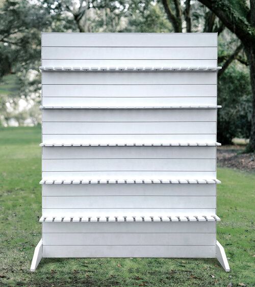 a tall white shelf sitting on top of a grass covered field with trees in the background