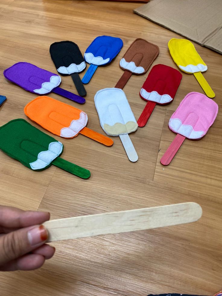 a person is holding a wooden spoon with different colored popsicles on it