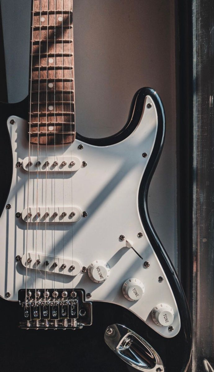 an electric guitar sitting on top of a black table next to a wall and window