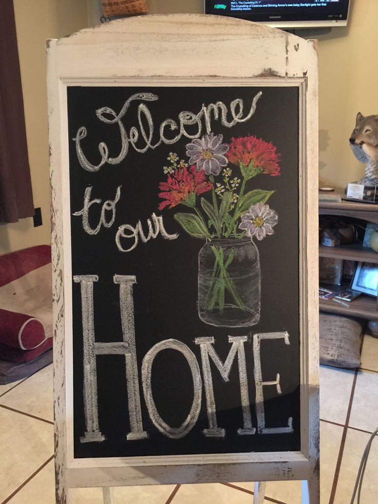 a chalkboard sign that says welcome to our home with flowers in a mason jar