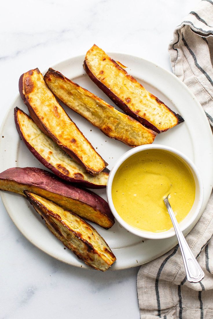 grilled eggplant sticks on a white plate with a bowl of dipping sauce