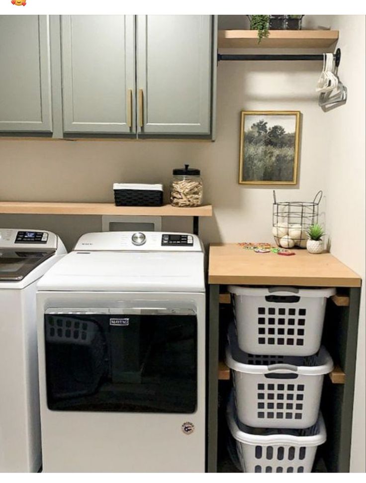 a washer and dryer in a small laundry room with wooden shelves above them