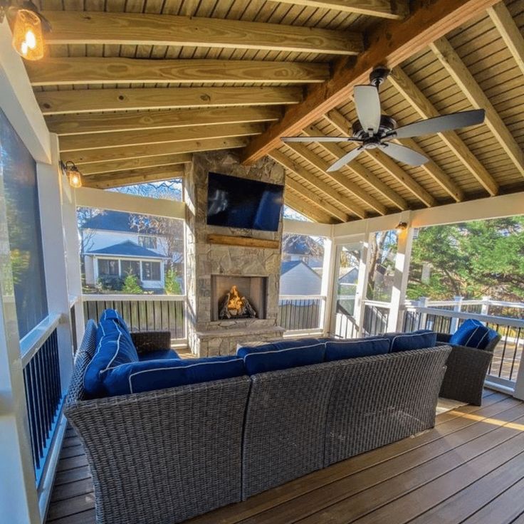 a covered porch with couches and a fireplace