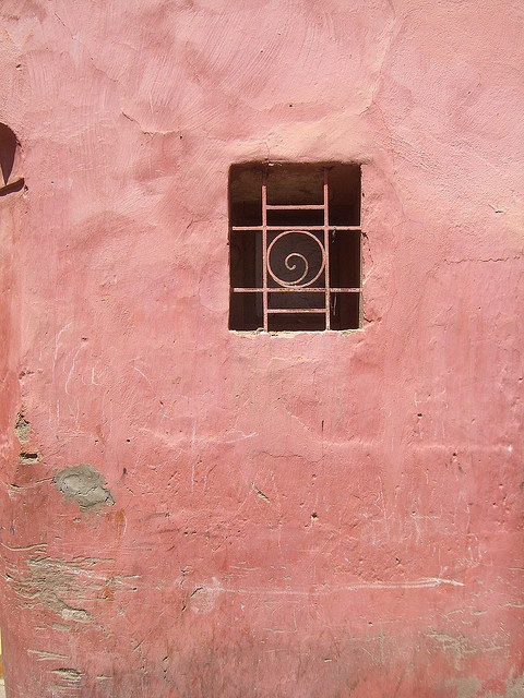 a pink building with a small window on the side