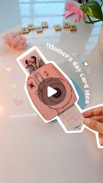 a person holding up a sticker with the image of a polaroid camera on it