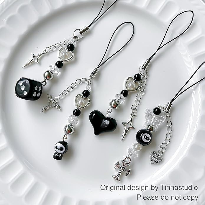 three necklaces on a white plate with black and white charms