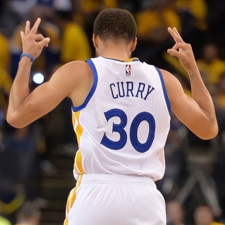 a male basketball player in a white and blue uniform with his hand up to the sky