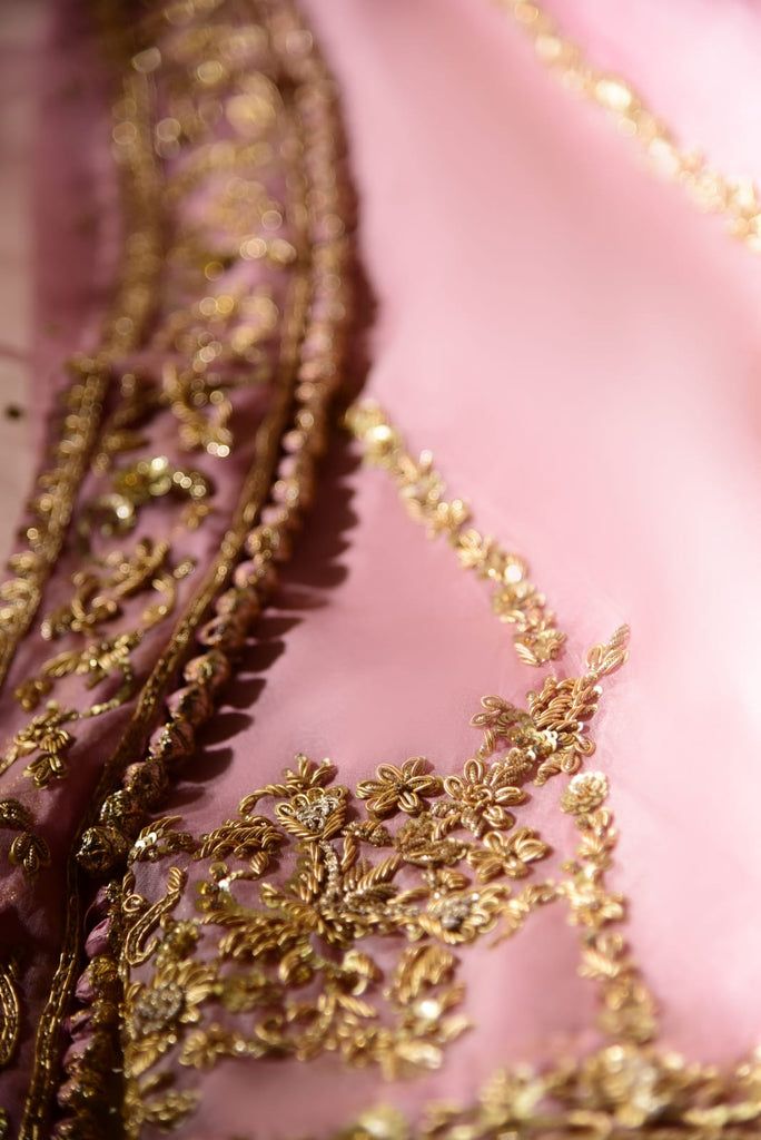 a close up view of a pink dress with gold trimmings and beads on it