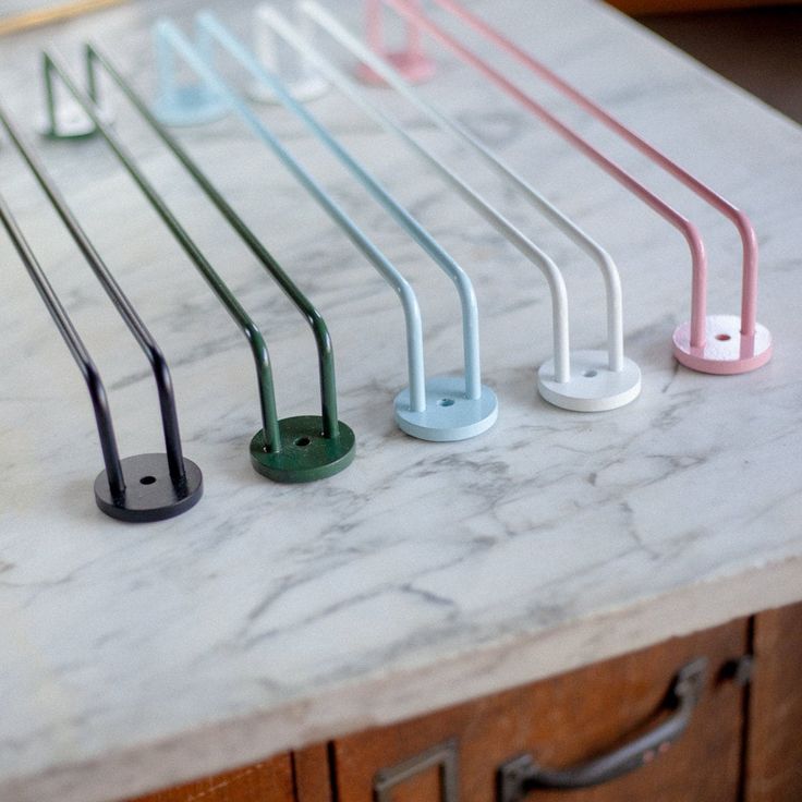 four different colored handles on a marble counter top with drawers in the backround