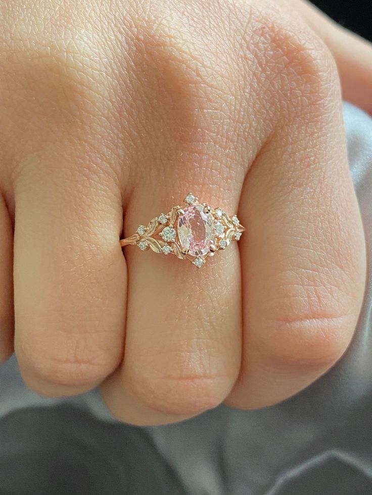 a woman's hand with a pink diamond ring on it