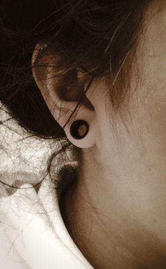 a close up of a person's ear with hair blowing in the wind behind them