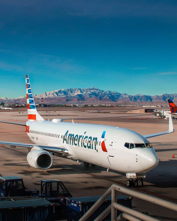 an american airlines plane is parked on the tarmac with mountains in the back ground