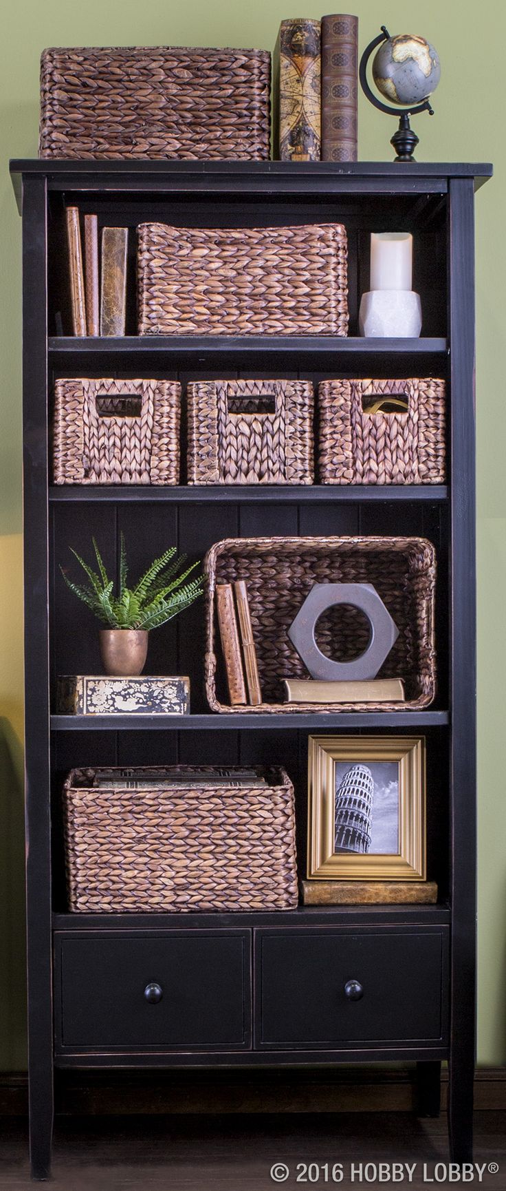 a black bookcase with wicker baskets on top