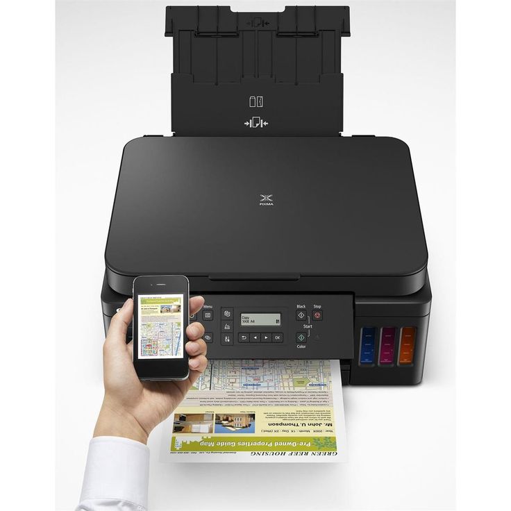 a person holding a cell phone next to an inkjet printer with the scanner open