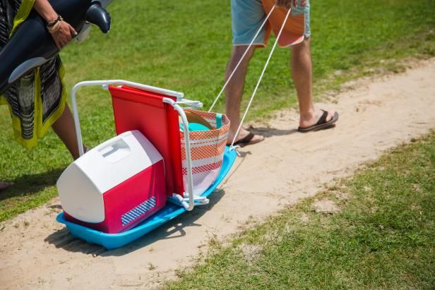 two people standing next to each other near a cart with coolers in it on the grass