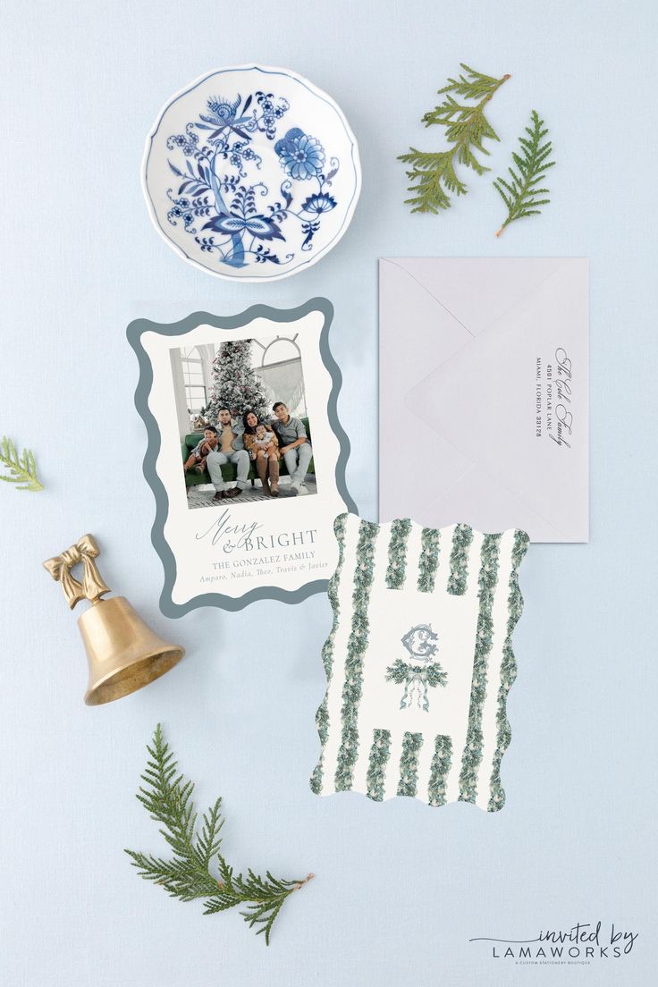 an assortment of christmas cards and decorations on a blue background with evergreen branches, pine cones, and a bell