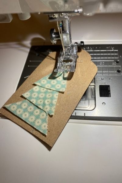 the sewing machine is next to some pieces of paper on top of a laptop computer