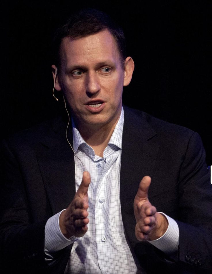 a man giving a thumbs up while sitting in front of a black background with headphones on his ears