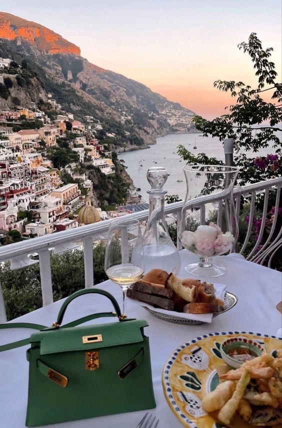 a table with food and drinks on it overlooking the ocean in positi, italy