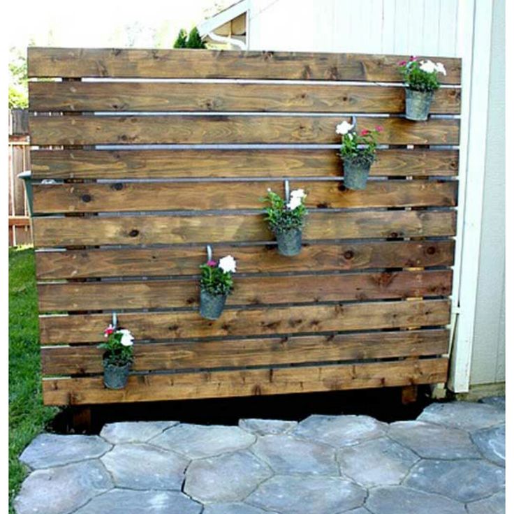 a wooden pallet with flower pots attached to it and some rocks on the ground