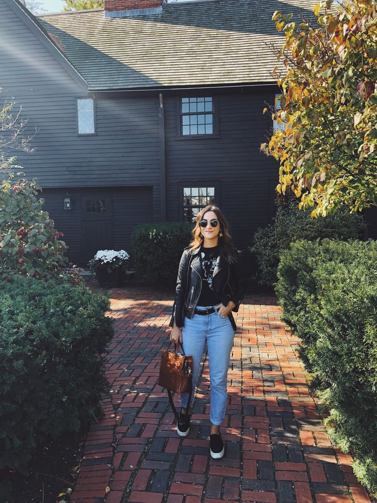 a woman walking down a brick walkway in front of a house