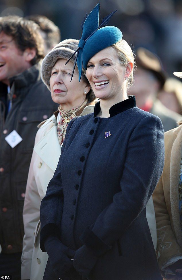 a woman wearing a blue hat with feathers on her head and other people in the background