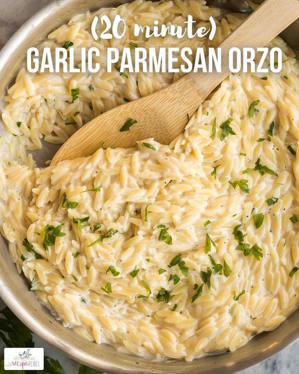 a pan filled with pasta and parmesan cheese next to a wooden spatula