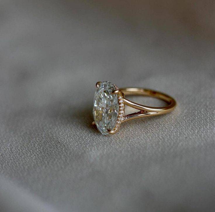 a close up of a ring on a white cloth with a diamond in the center