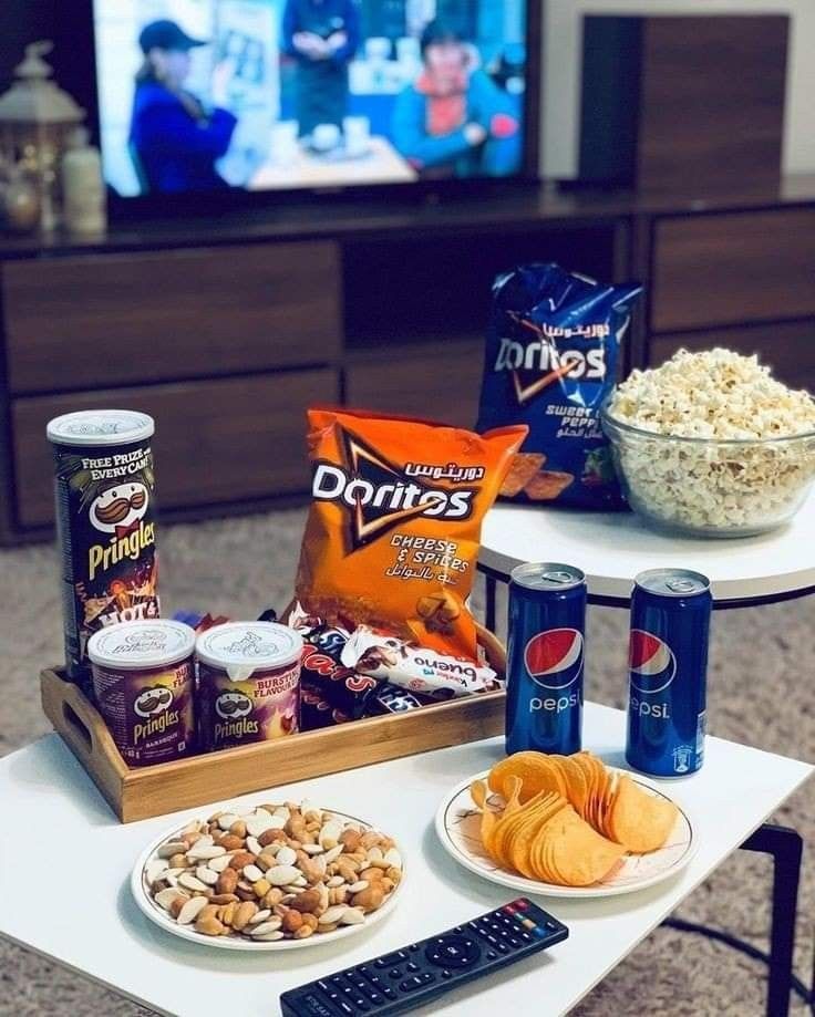 snacks and drinks on a table in front of a television