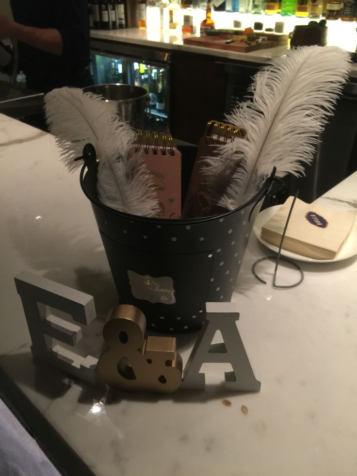 a metal bucket with some feathers in it on top of a counter next to a bar