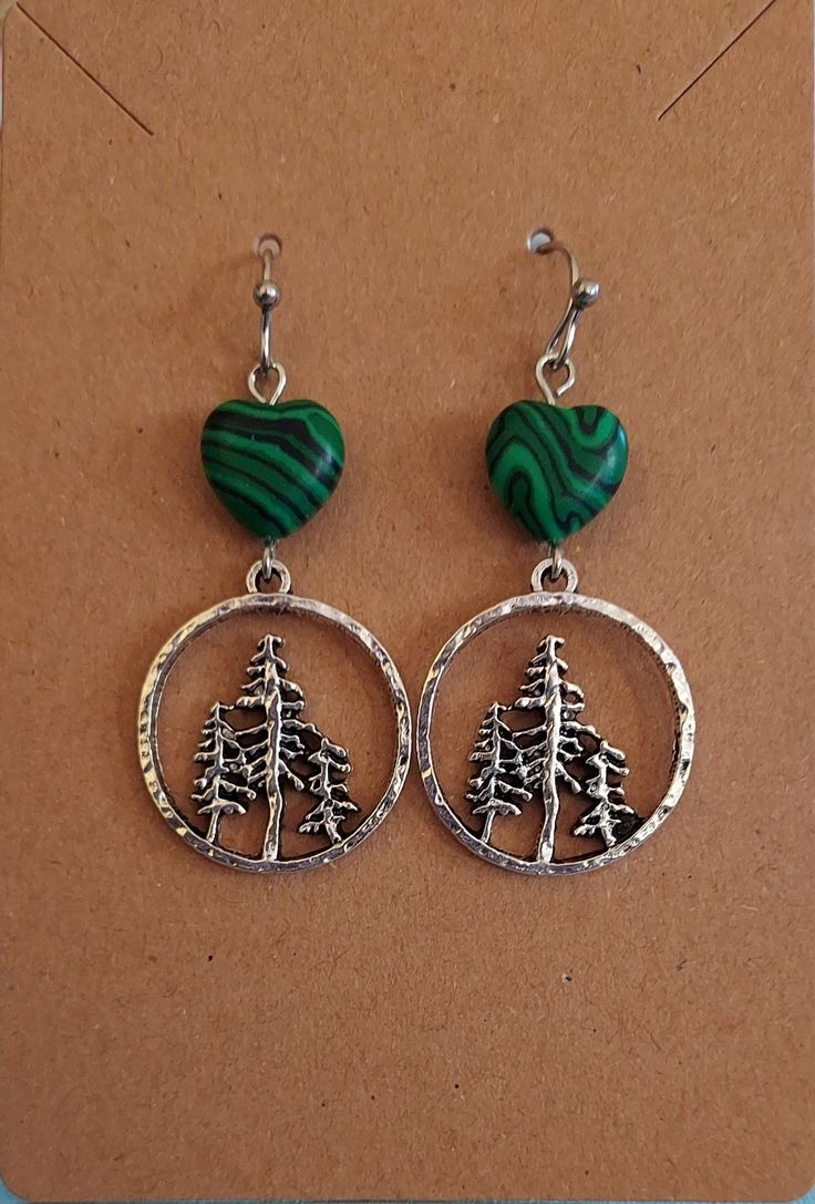 These pretty evergreen earrings remind me of the beloved PNW.  They're accented with a green stone heart bead and hang on stainless steel hooks. Green Heart-shaped Sterling Silver Jewelry, Green Sterling Silver Heart Jewelry, Handmade Green Hoop Earrings For Gift, Green Metal Dangle Hoop Earrings, Green Dangle Metal Hoop Earrings, Green Dangle Hoop Earrings In Metal, Nickel Free Green Metal Earrings, Nickel-free Green Metal Earrings, Green Heart Drop Earrings For Gifts