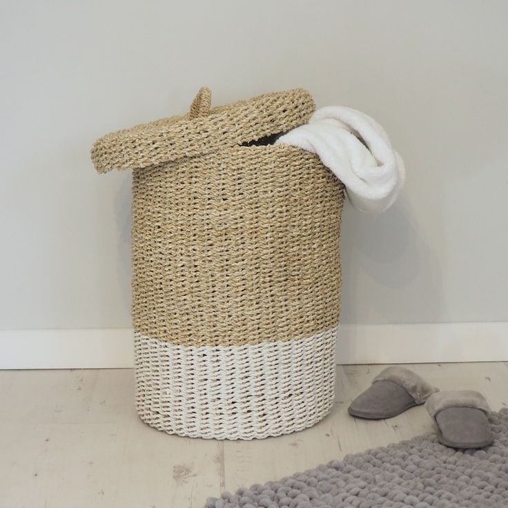 a white and beige basket sitting on the floor next to a pair of slippers