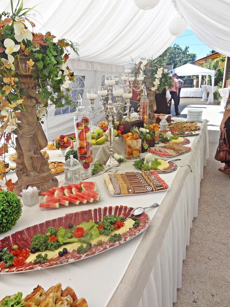 a long table with many plates and food on it, all covered in white linens