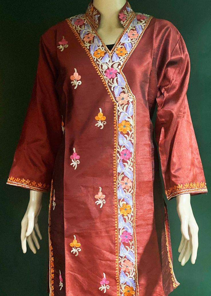 Embroidered Tunic Crafted from raw Silk, designed in Classic Kashmiri Aari embroidery.  Match it with a pair of denims or leggings perfect for Women and Girls a classic tunic that never goes out of fashion. ThisTunic features intricate  embroidery on the neckline, sleeves, the side hem and motif on the front. A combination of vibrant shades with a beautiful play of colors. Color: silk Red Maroon -Color can vary due to lighting. All sizes  are approx.  Size: USA, M  Chest:40 inch.  Shoulder: 17 inch.  Sleeve length: 18 inch  Length: 36 inch. Fabric: Raw Silk- Dry clean or hand wash, iron on low heat. Made in a smoke and pet free home. Made in Kashmir, India Bohemian Embroidered Traditional Wear For Summer, Fitted Tunic With Resham Embroidery For Festive Occasions, Summer Festive Kurta With Embroidered Border, Fitted Floral Embroidery Blouse For Eid, Fitted Tunic Kurta With Dabka Work, Embroidered Traditional Salwar Kameez, Floral Embroidered Raw Silk Salwar Kameez For Spring, Folk Style Dress With Resham Embroidery For Traditional Ceremonies, Long Sleeve Embroidered Dress With Dabka Work