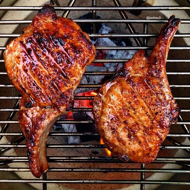 two steaks are cooking on the grill