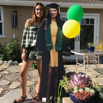 two women standing next to each other in front of a house with balloons and flowers