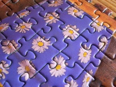 the puzzle is made up of purple and white daisies on a blue background with yellow centers