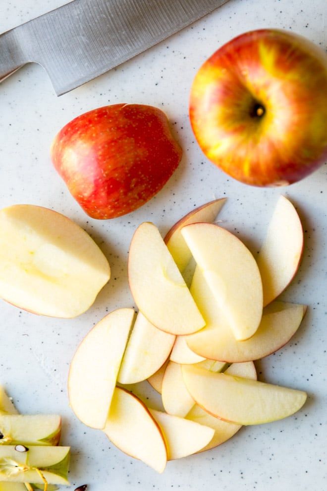 an apple and some sliced apples on a cutting board with a knife next to it