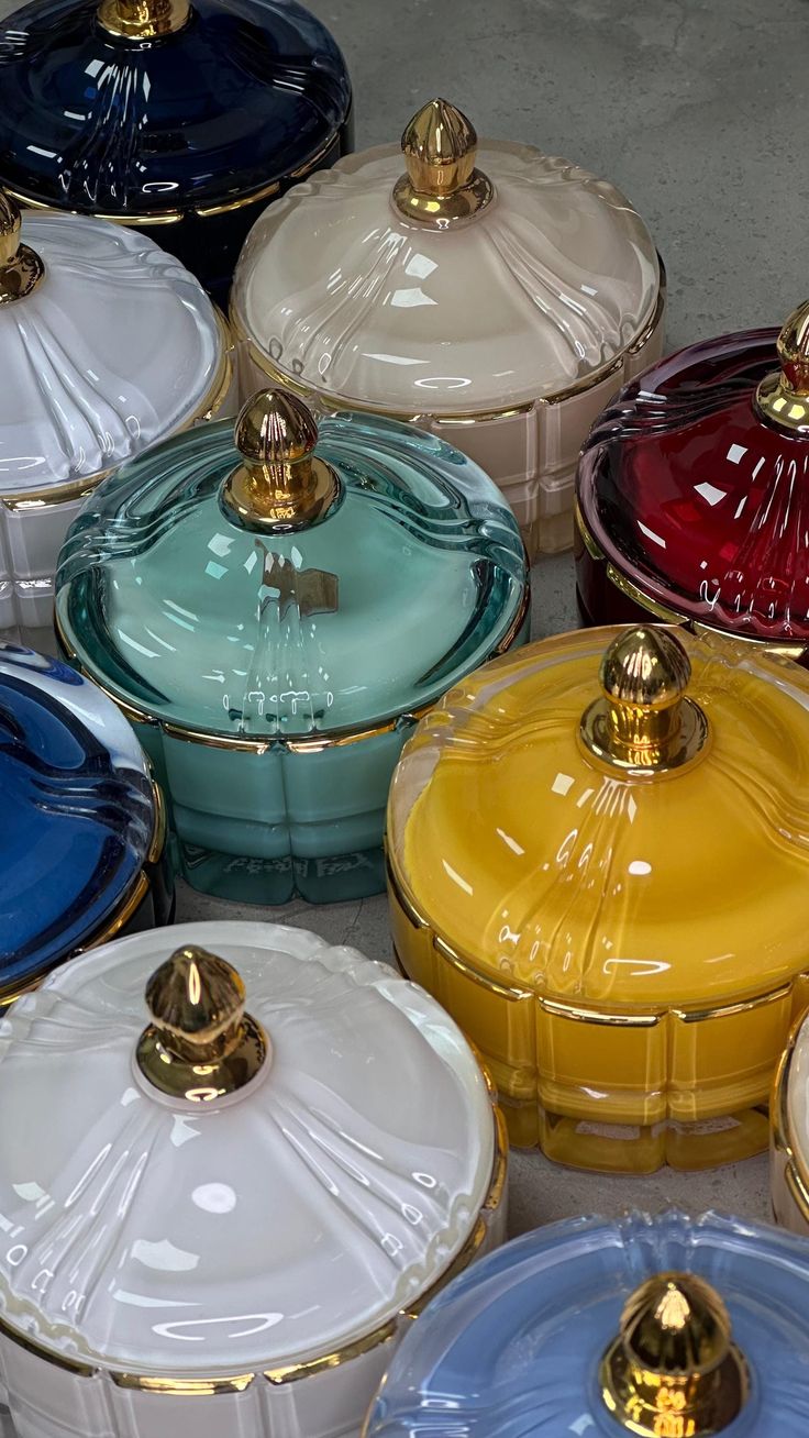 there are many different colored dishes on the table together and one has a gold top