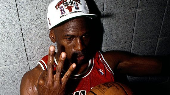 a man holding a basketball in his right hand and making the peace sign with his left hand