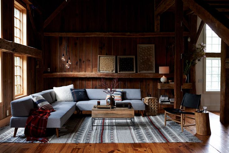 a living room with wood paneling and furniture on the floor, including a sectional couch