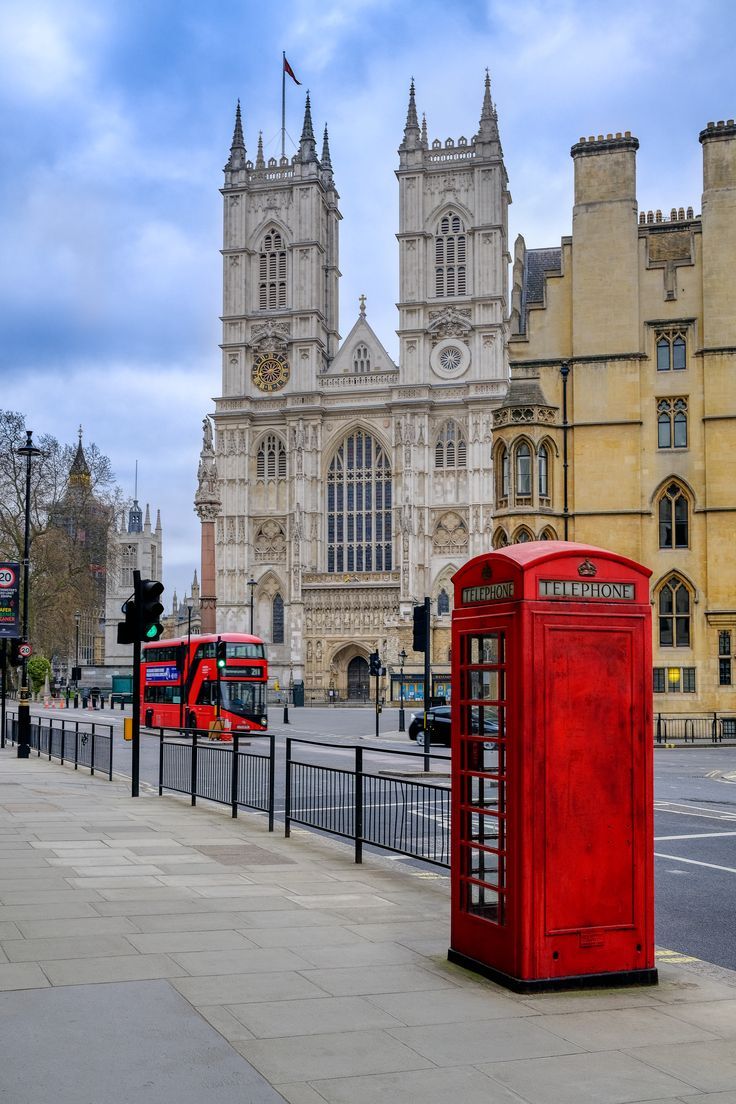 a red phone booth sitting on the side of a road next to a tall building